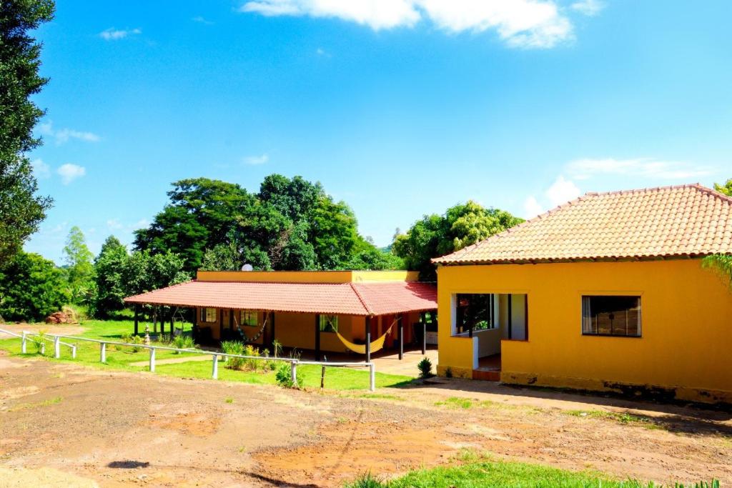 uma pequena casa amarela com um telhado vermelho em Pousada - Pesqueiro do Brasinha 