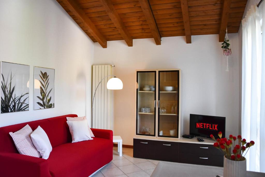 a living room with a red couch and a tv at CA' GIALLA 5 - sul Lago di Lugano, Dog friendly, Balcone & Parcheggio - in Cadegliano Viconago