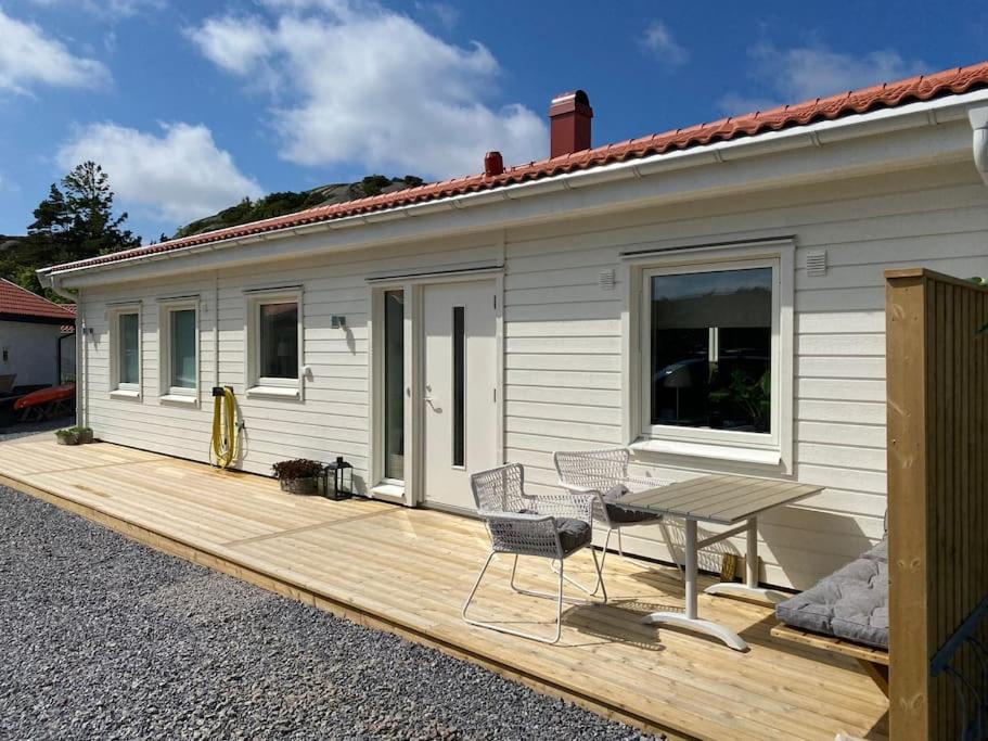 une terrasse en bois à côté d'une maison avec une table dans l'établissement Nybyggd villa med närhet till berg och hav, à Hunnebostrand