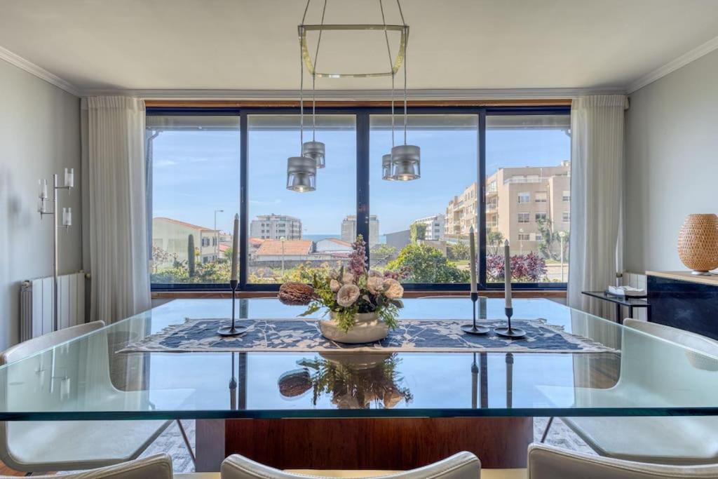 une salle à manger avec une table en verre et une grande fenêtre dans l'établissement Blue House by the Beach, à Leça da Palmeira