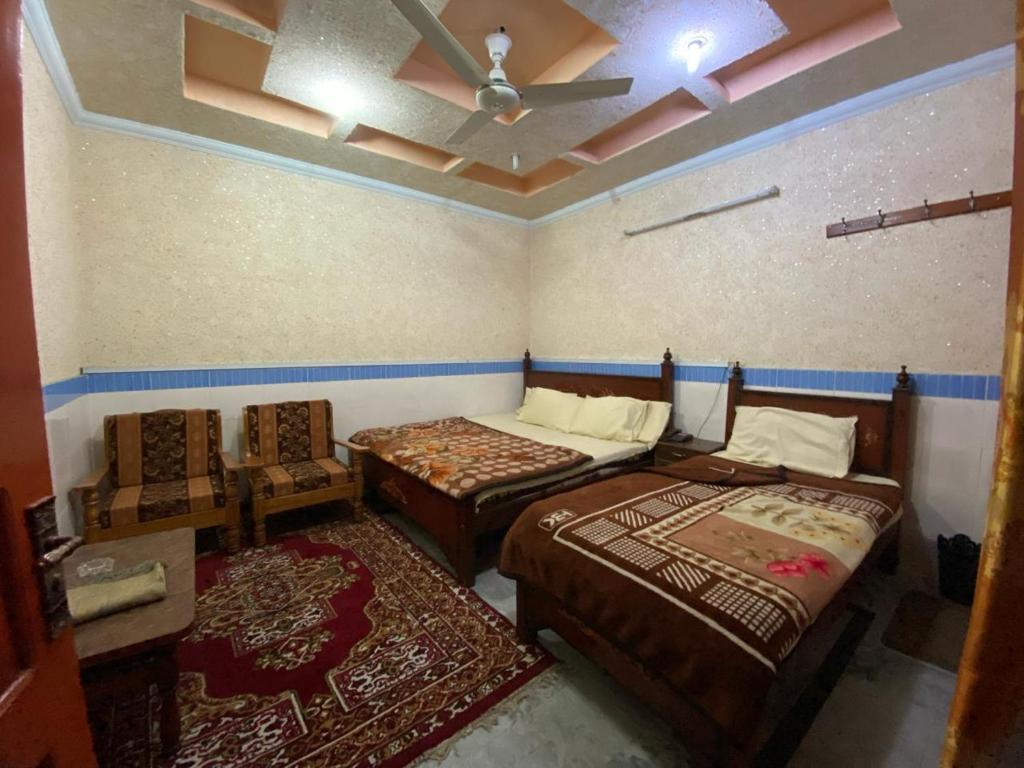 a bedroom with two beds and a ceiling fan at Zain Hotel Abbottabad in Abbottabad