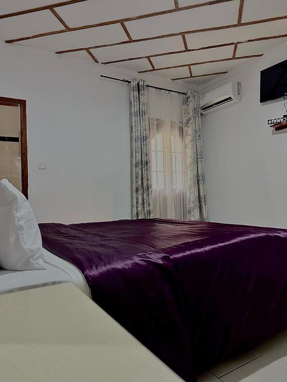 sypialnia z łóżkiem z fioletowym kocem w obiekcie Golf hills w mieście Jaunde