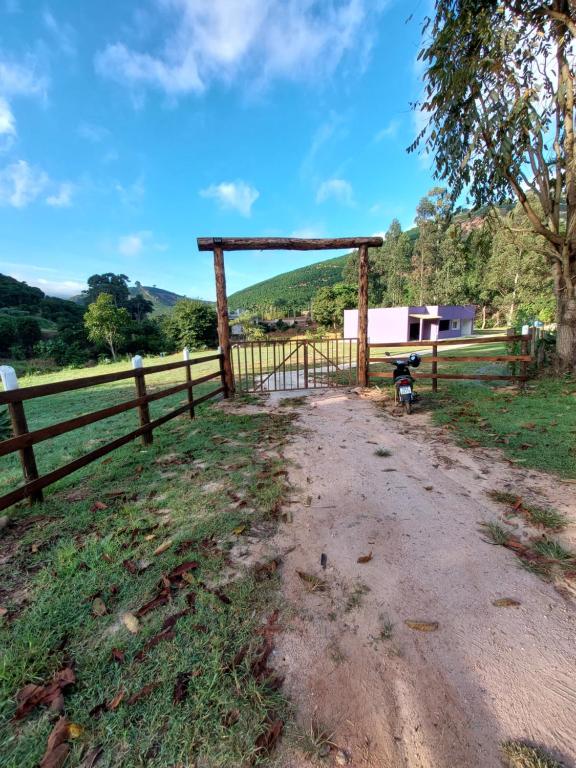 a wooden fence with a bench in a field at Chácara Aconchego na Serra in Caparaó Velho