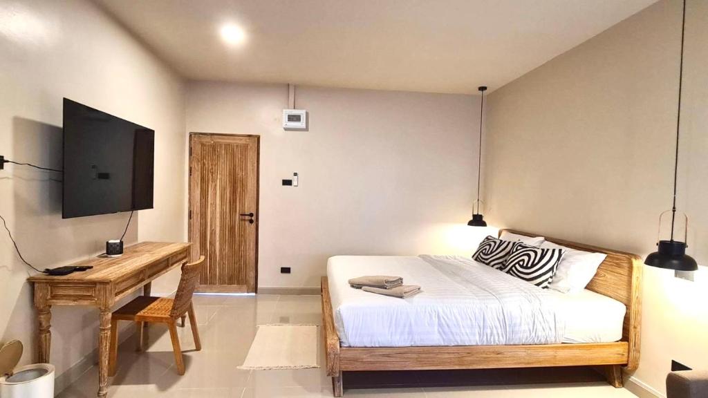 a bedroom with a bed and a desk and a television at VNL Stay in Trang