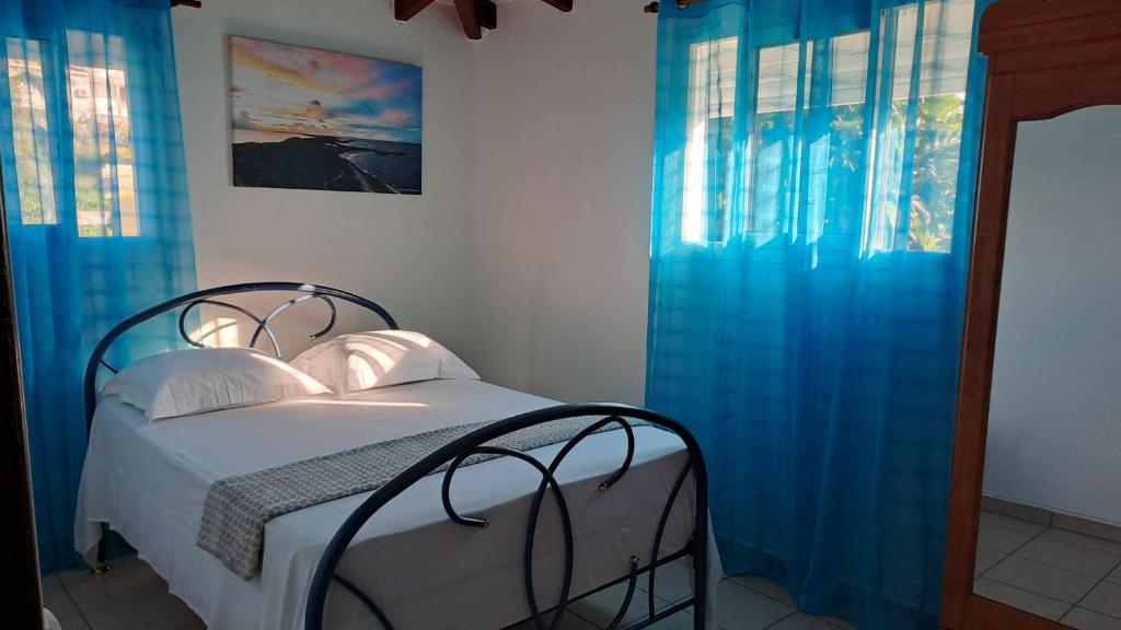 um quarto com uma cama com cortinas azuis em Soleil bleu em Les Abymes