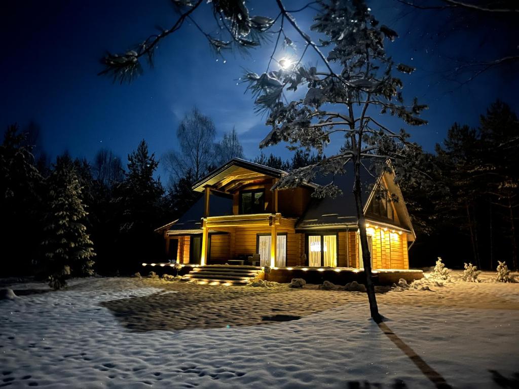 Una casa iluminada en la nieve por la noche en WoodStay, 