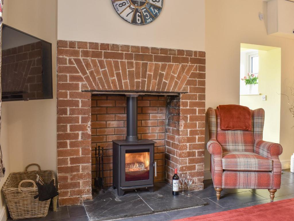 a brick fireplace with a chair and a clock at Fairholme in Bodfari