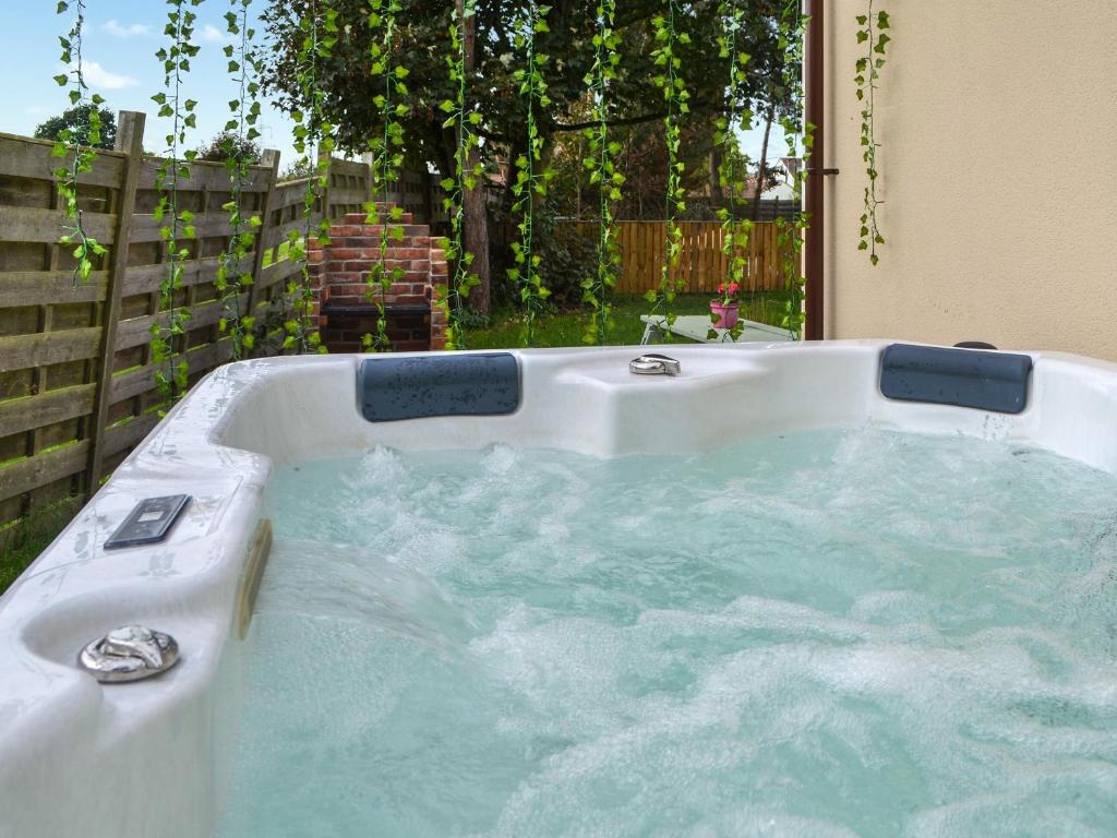 a jacuzzi tub in a backyard with a fence at Heatherdene - Fern Cottage in Wilberfoss