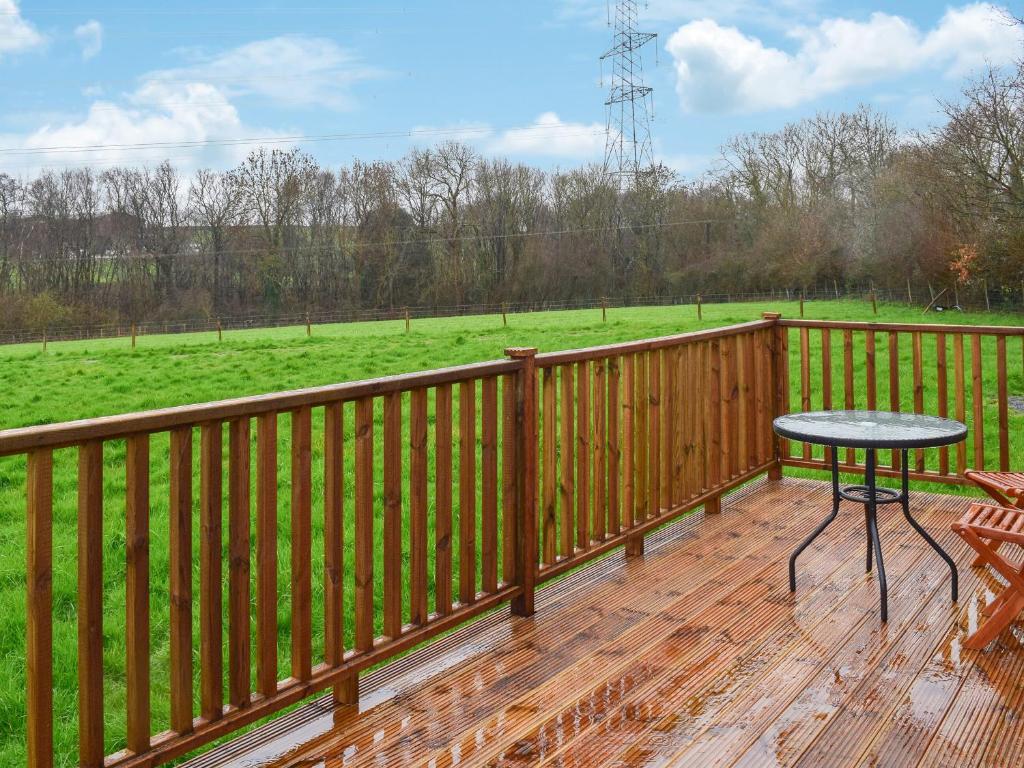 une terrasse en bois avec une table et un champ dans l'établissement Badgers - Uk46750, à Herstmonceux