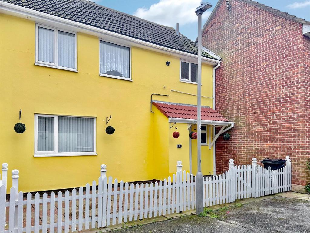 une maison jaune avec une clôture blanche devant elle dans l'établissement Sunrise Villa, à Clacton-on-Sea