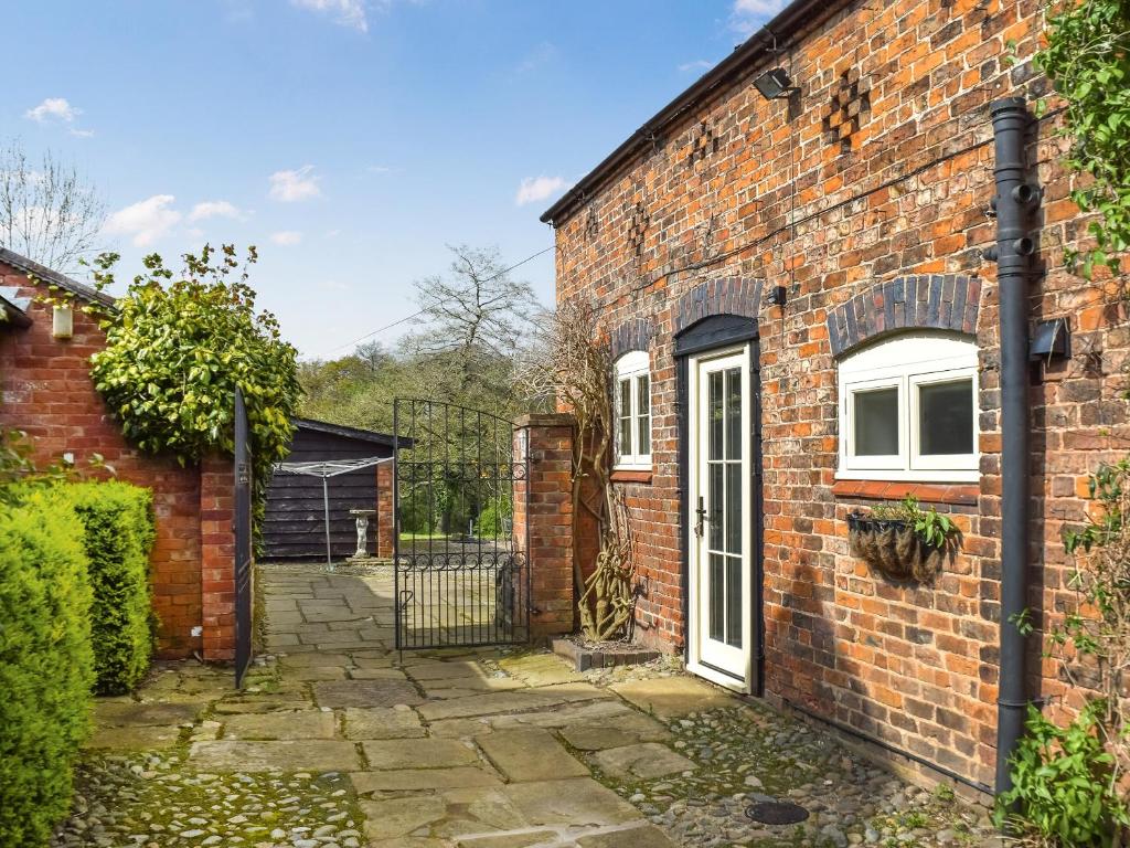 an old brick house with a white door at The Coach House Annexe in Tilston