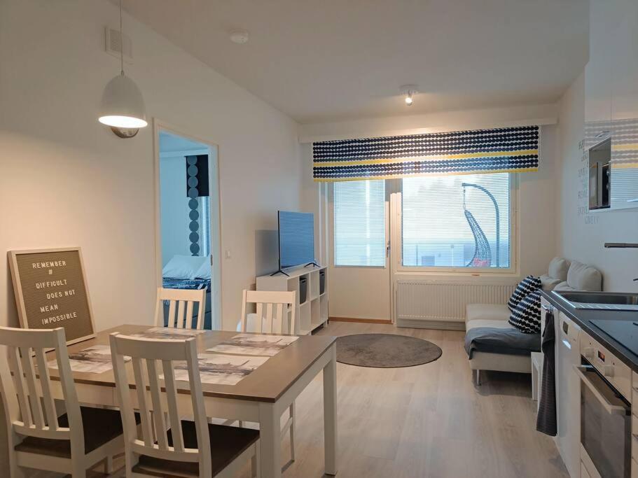a kitchen and living room with a table and chairs at Uusi kaksio parvekkeella ja autopaikalla in Joensuu