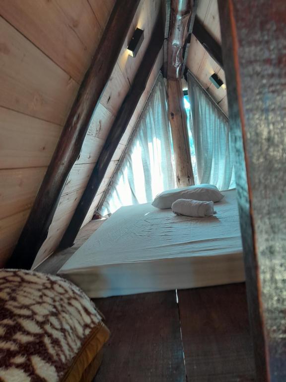 a bed in a wooden room with a window at Fazenda Invernada Grande Turismo Rural in Bom Jardim da Serra