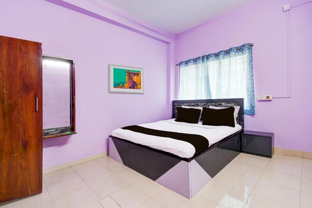 - une chambre avec un lit aux murs violets et une fenêtre dans l'établissement SPOT ON Hotel Sunshine Lodging, à Āsansol