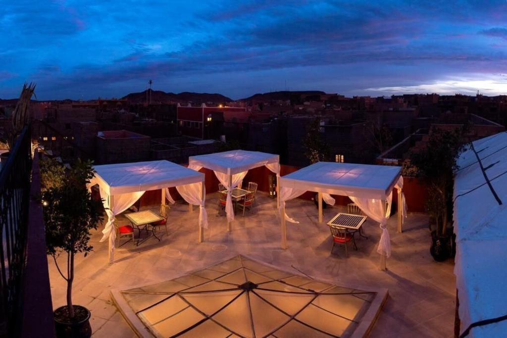 a group of tables and chairs on a patio at night at Riad Ksar Aylan in Ouarzazate
