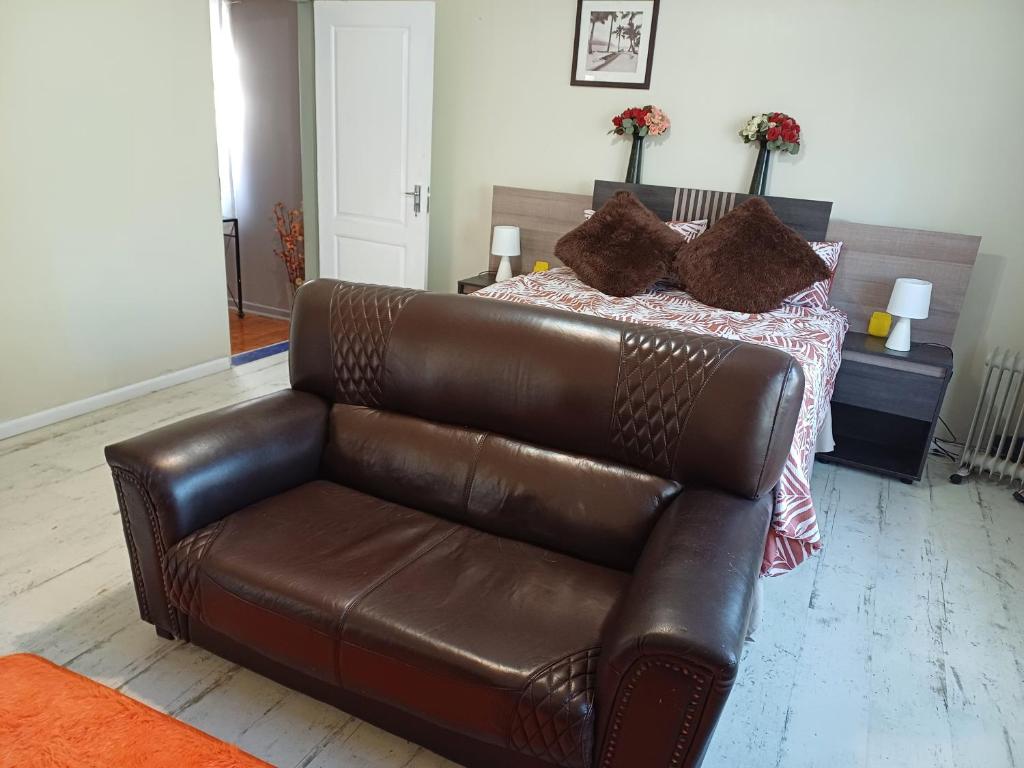 a brown leather couch in a bedroom with a bed at Serene on 5 Cologne in Germiston