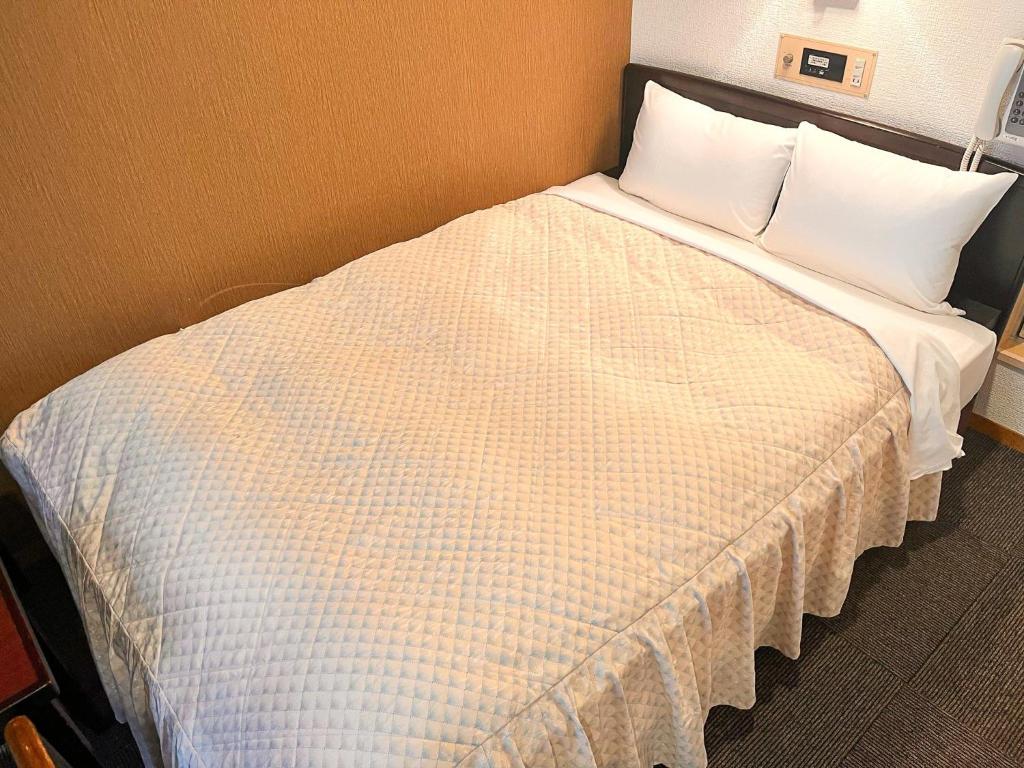 Hotel Sho Sapporo - Vacation STAY 55602v في سابورو: سرير بشرشف ووسائد بيضاء في الغرفة