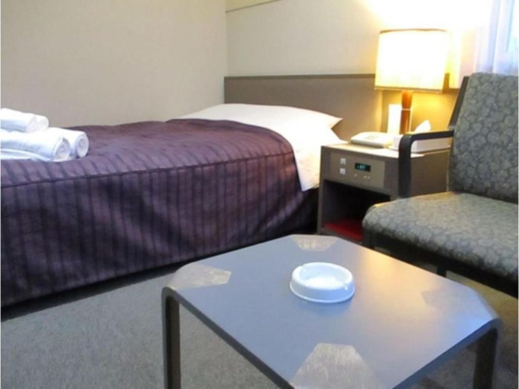 函館市にあるHotel Heart INN Hakodate - Vacation STAY 56675vのベッド、椅子、テーブルが備わるホテルルームです。