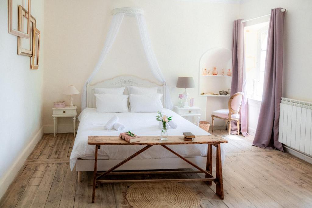 1 dormitorio con cama blanca y mesa en Chambres d'hôtes B&B - Château de Sienne proche Avignon Orange Piscine Rivière, en Chusclan