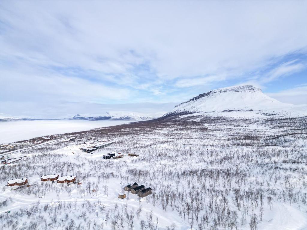 einen schneebedeckten Hügel mit Bäumen und einem Berg in der Unterkunft Naali in Kilpisjärvi