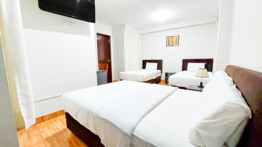 1 dormitorio con 2 camas y TV de pantalla plana en Samaná, en Tacna
