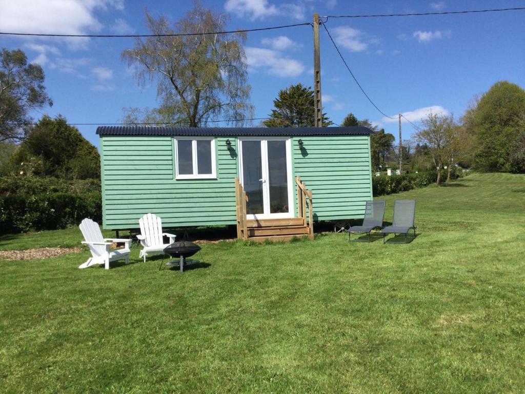 une petite maison verte avec des chaises blanches dans la cour dans l'établissement la petite maison verte, à Plévin