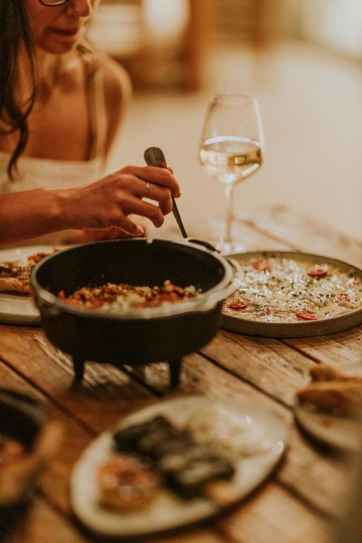 a woman eating a pan of pizza with a glass of wine at Ergon Beach House Nikiti in Nikiti