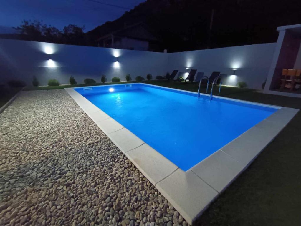 a swimming pool in a backyard at night at Sasha Apartment and Swimming Pool in Gornje Selo