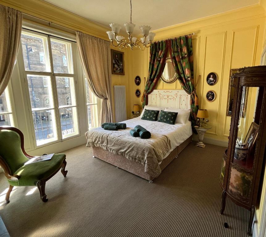 a bedroom with a bed and a chair and windows at Chez Vivienne in Ilkley