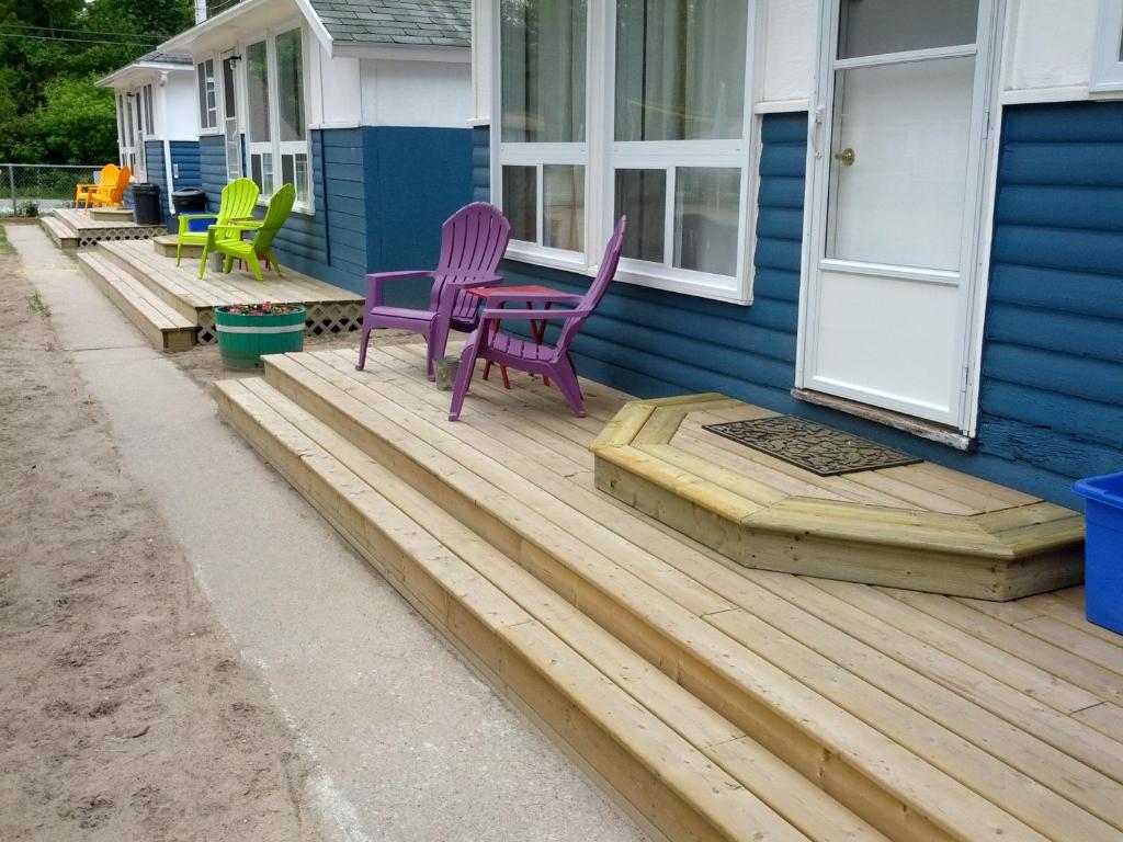 a porch with purple and green chairs on a house at Wu Wu's Cabins in Wasaga Beach