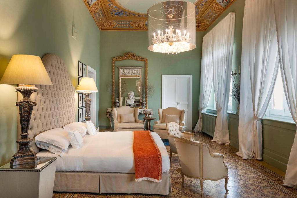 a bedroom with a large bed and a chandelier at Seven Rooms Villadorata in Noto