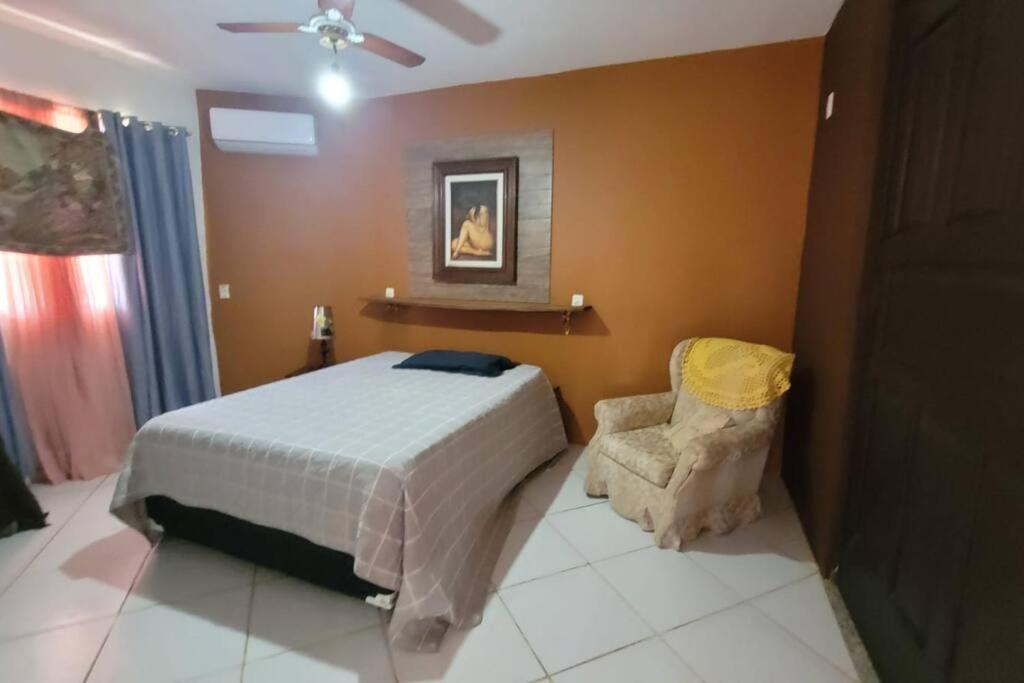 - une chambre avec un lit et une chaise dans l'établissement Villa Blue Point - Chácara com piscina e 4 quartos, à Vila Velha