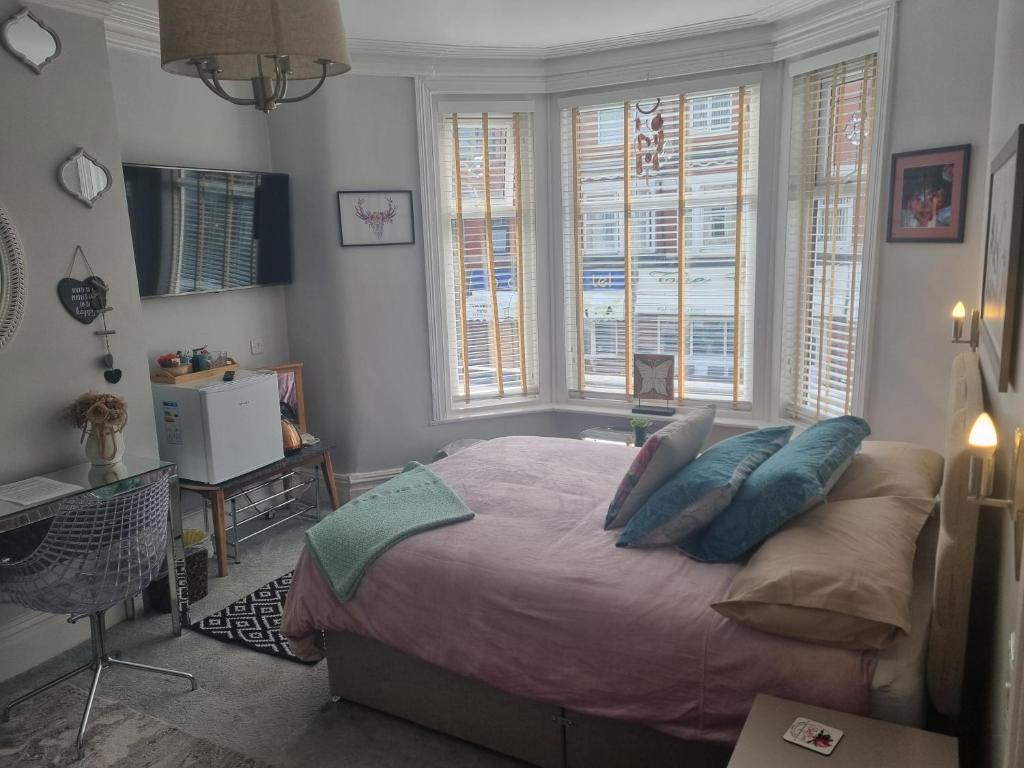 TIFFY'S PLACE Adult Guest House في بلاكبول: غرفة نوم بسرير مع مخدات ونوافذ