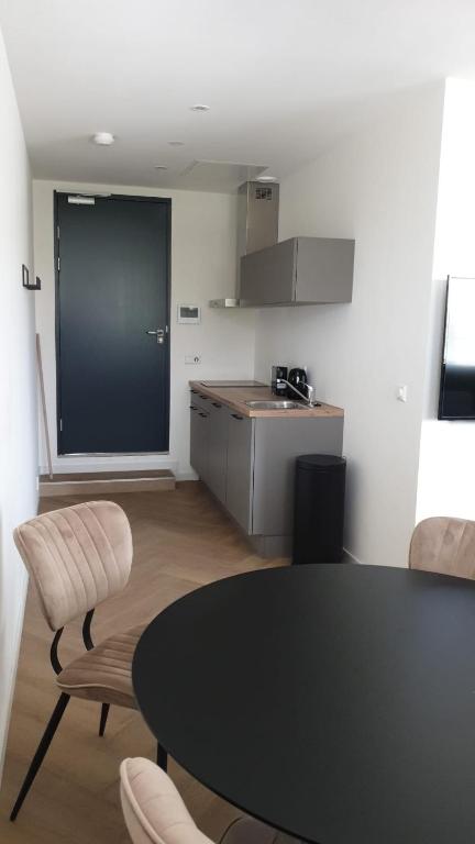 Zimmer mit einem Tisch und Stühlen sowie einer Küche in der Unterkunft Diktbiy stadion -studio D in Eindhoven