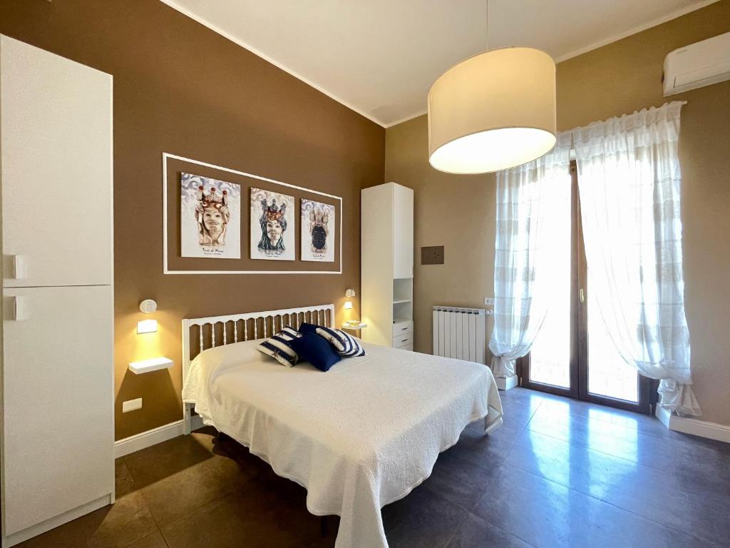ein Schlafzimmer mit einem weißen Bett mit blauen Kissen darauf in der Unterkunft Casa Gramsci Anzio Centro in Anzio