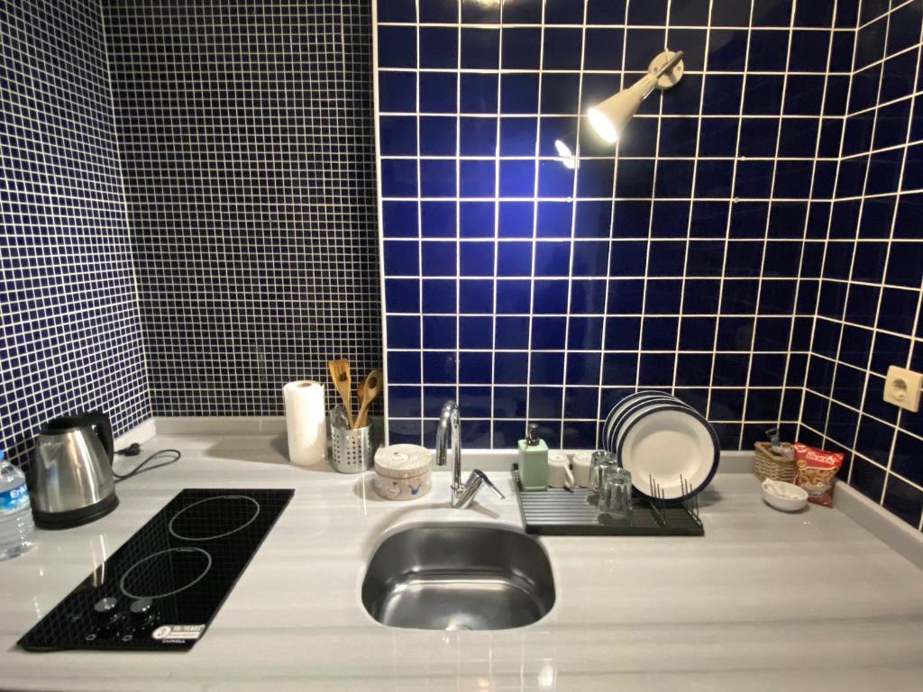 a bathroom with a sink and a blue tiled wall at Petek Pansiyon Fenerbahce Kadikoy in Istanbul