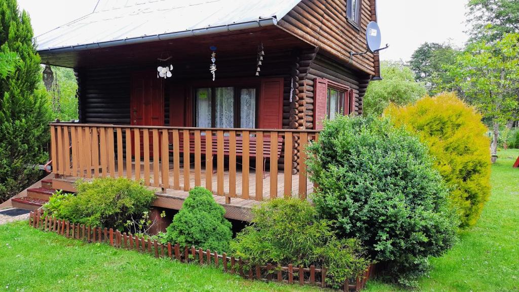 a log cabin with a porch and some bushes at Klimatyczny domek z łodką nad jeziorem in Dobre Miasto