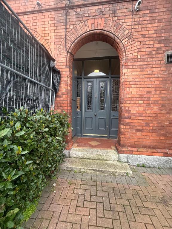 een ingang naar een bakstenen gebouw met een blauwe deur bij Superb Location 3 MIN TO RDS, AVIVA, D4 2 BED APARTMENT in Dublin