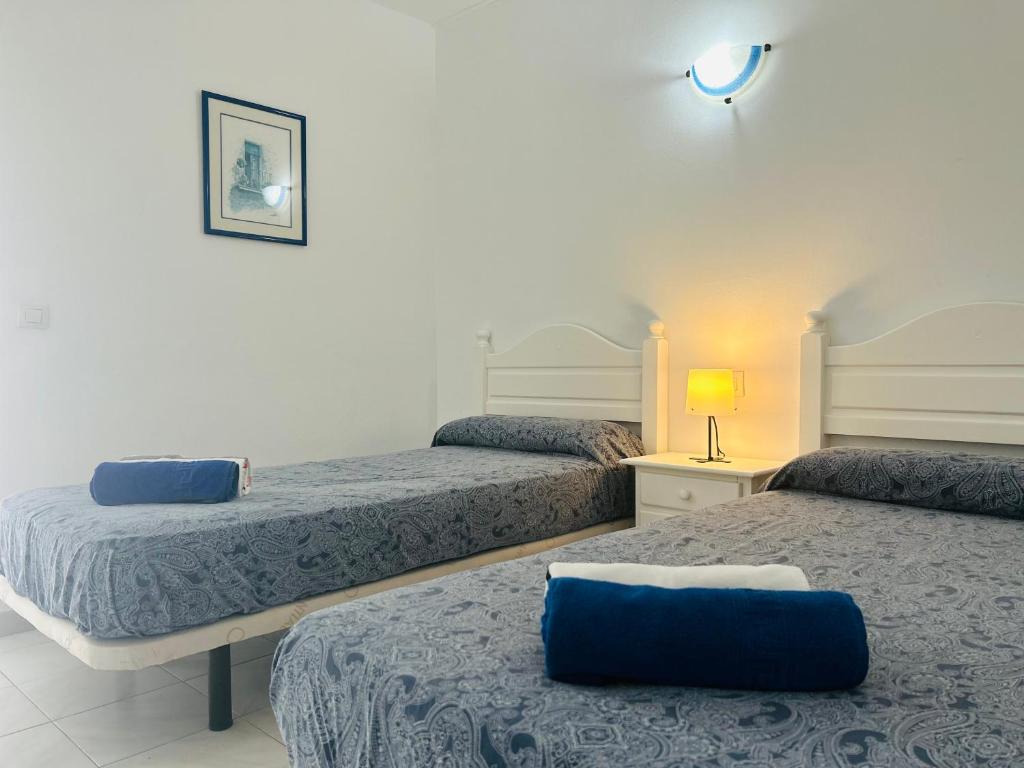 um quarto com 2 camas com lençóis azuis e um candeeiro em -MONTORIAN Apartments -LANZAROTE em Tías