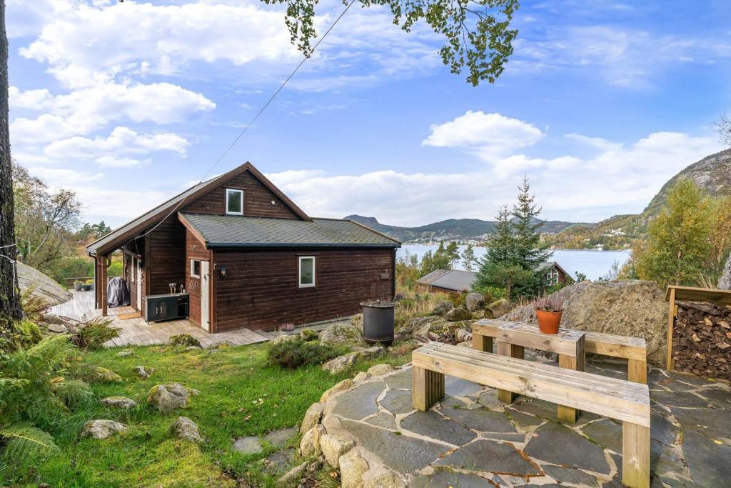 une cabane en bois avec un banc devant elle dans l'établissement Sjarmerende hytte nær sjøen - 4 soverom, à Strand