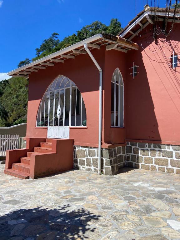 a red church with a white door and stairs at Casa da Varanda Próximo Centro in Petrópolis