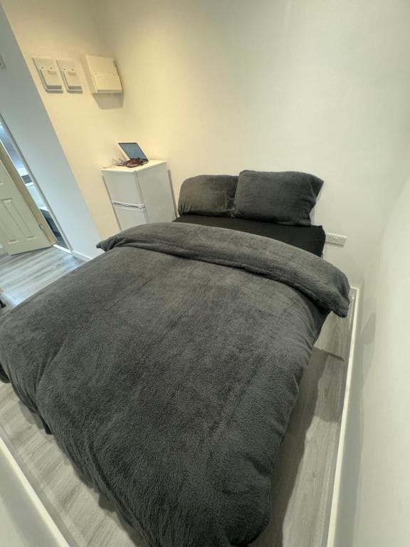 - une chambre avec un lit et une couverture grise dans l'établissement Enjoy the comfort at beautiful studio, à Luton