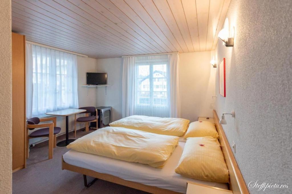 a bedroom with two beds and a table and a desk at Hotel Krone Uetendorf in Uetendorf