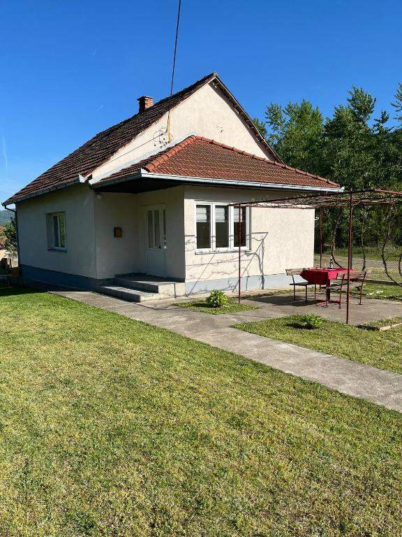 una piccola casa bianca con una panchina rossa davanti di Vikendica Lazic a Ljubovija