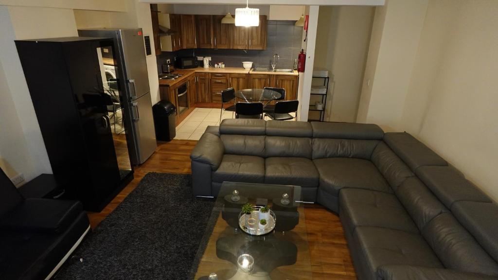 a living room with a couch and a kitchen at The Swanky Apartment Manchester in Manchester