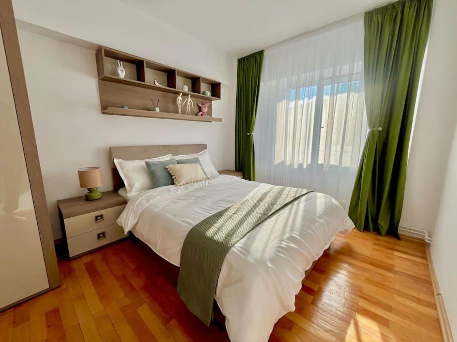 a bedroom with a bed and a window with green curtains at Valcea Northside Spacious Apartment in Râmnicu Vâlcea