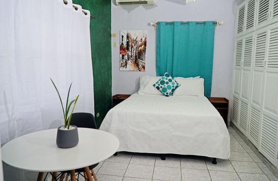 a bedroom with a bed and a white table and a table at Hotel Boutique Rosse in San Pedro Sula