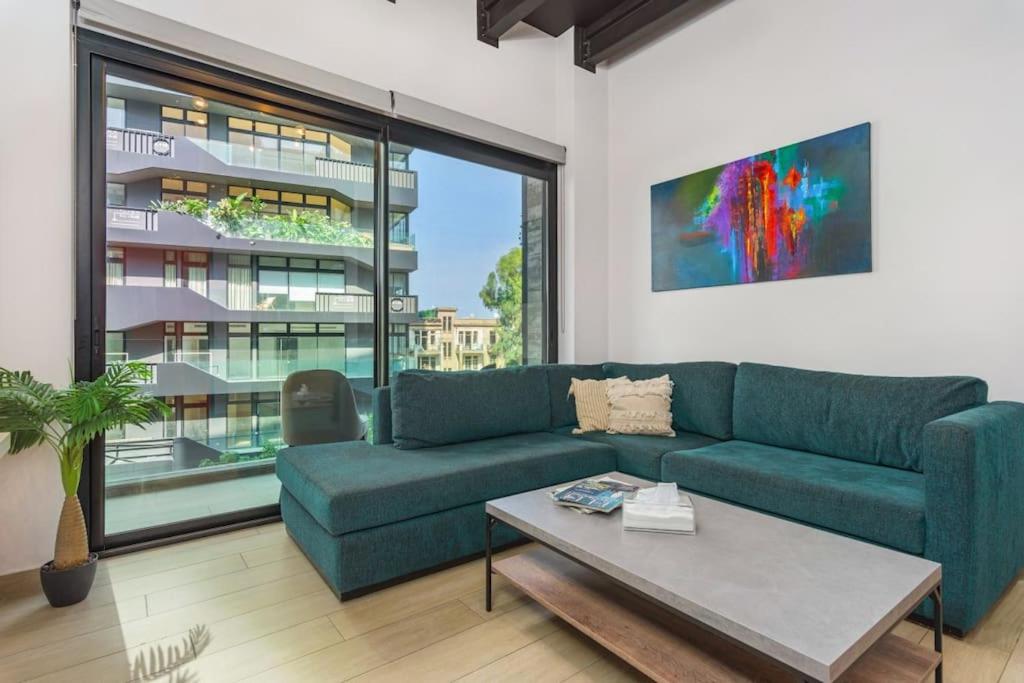 a living room with a blue couch and a large window at Al Amine - 202, 1-BR in Mar Mikhael in Beirut