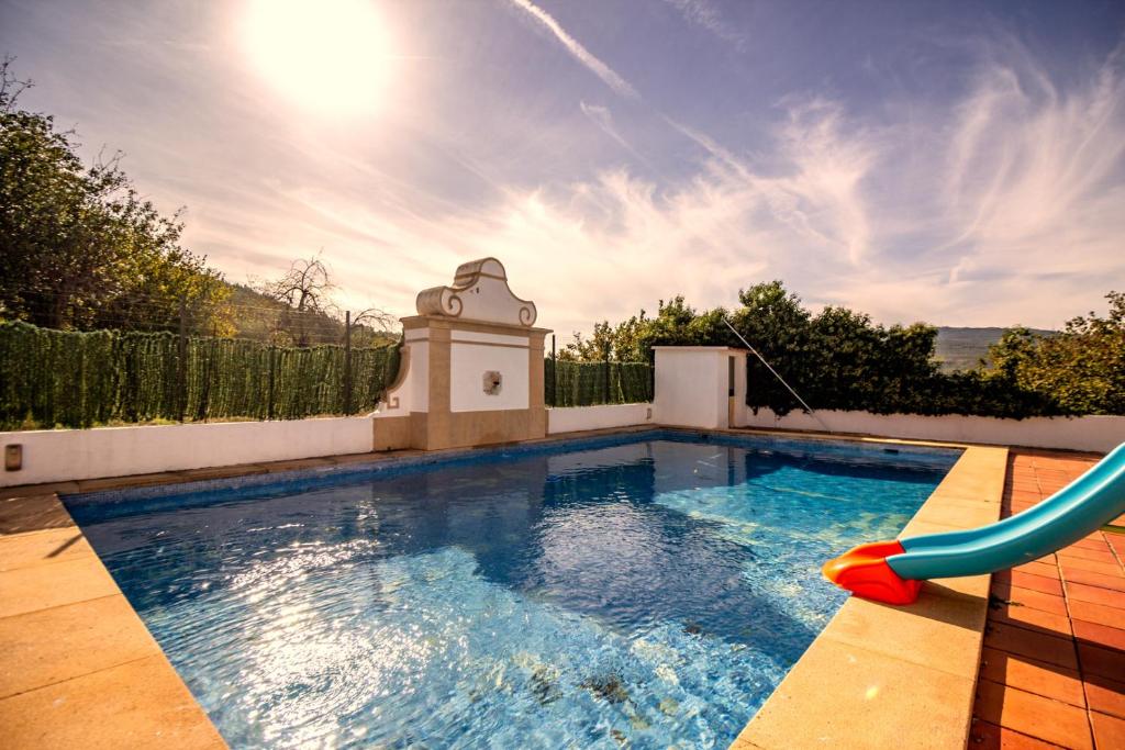 a swimming pool with a slide in a backyard at Casa Do Ginjal by NaturAlegre in Marvão