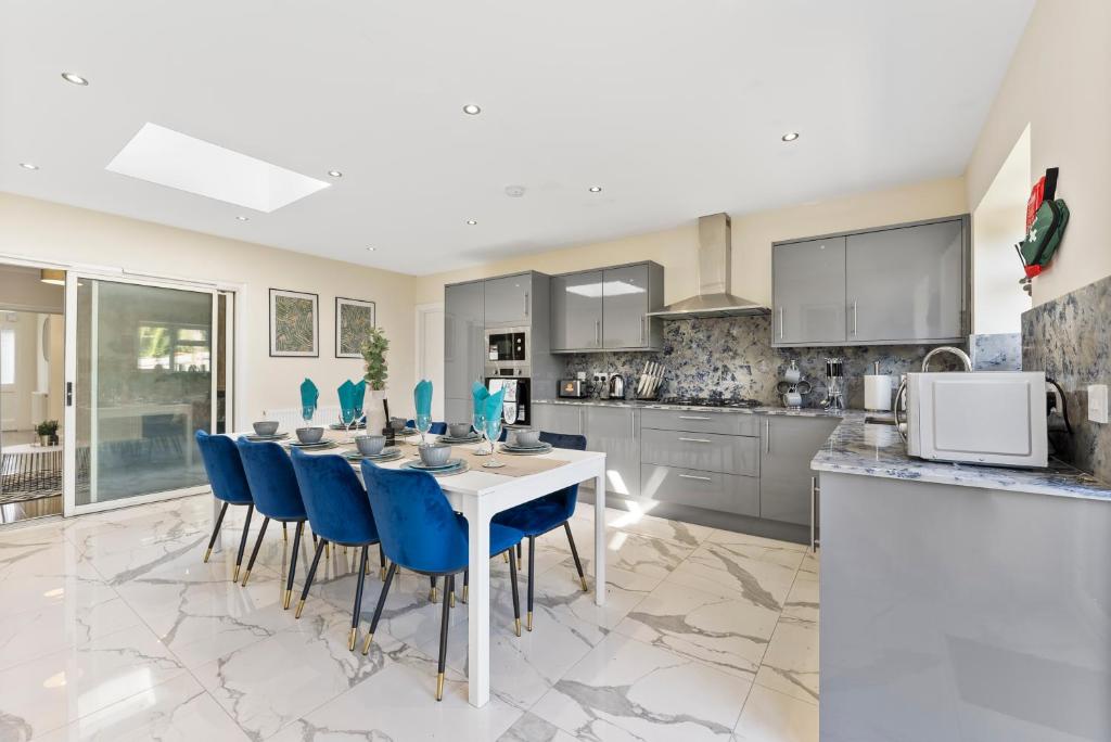 a kitchen with a white table and blue chairs at Stunning 6 Bed in Wembley - Parking - Garden in London
